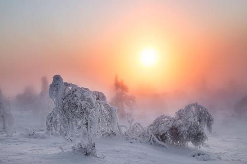 a snow covered mountain with the sun in the background at Tupasvilla in Saariselka