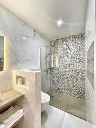 a white bathroom with a shower and a toilet at Luna Ensuites Centro in Málaga