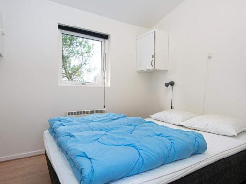 um quarto com uma grande cama azul e uma janela em Holiday Home Haregade II em Hovborg