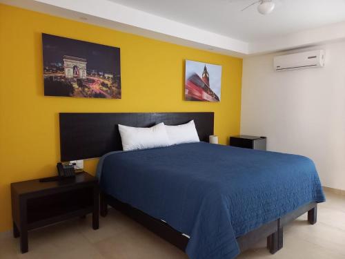 a bedroom with a blue bed and a yellow wall at Casa Blanca Hotel in Jalpan