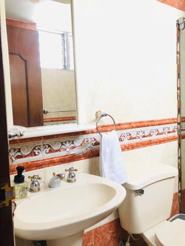 a bathroom with a sink and a toilet and a mirror at Alojamiento Laureles la 33 in Medellín