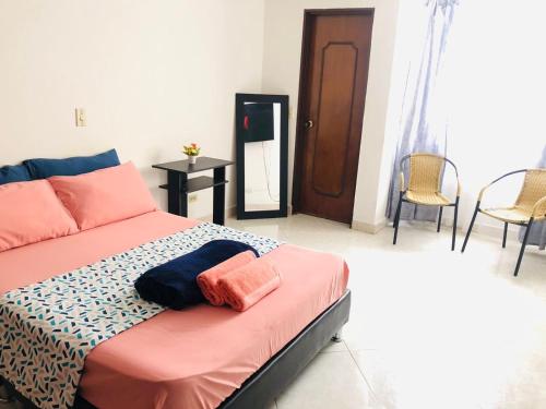a bedroom with a bed and a mirror and chairs at M&N Alojamiento es una habitación en un apto in Medellín