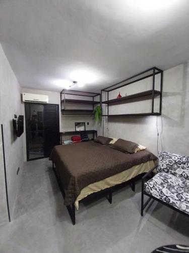 a bedroom with a large bed and a chair at FLAT PALLADIUM - DE FRENTE - novo in São Vicente