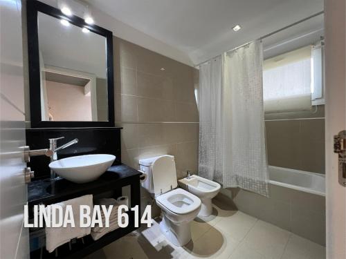 uma casa de banho com um lavatório, um WC e um espelho. em Linda Bay 614 em Mar de las Pampas