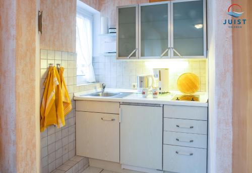 a small kitchen with white cabinets and a sink at Haus Petra 131 - Ferienwohnung 1 in Juist
