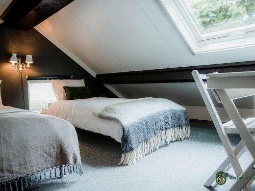 a attic bedroom with two beds and a window at Spacious Farmhouse near Forest in Heeze-Leende in Leende