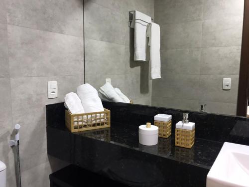 ein Badezimmer mit einer schwarzen Theke, Handtüchern und einem Spiegel in der Unterkunft Maravilhoso Loft vista mar OCEANVIEW in Niterói