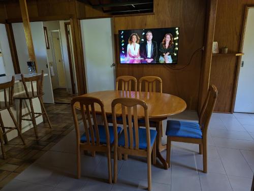 a dining room table and chairs with a tv on the wall at Gumnut Glen Cabins in Yeppoon