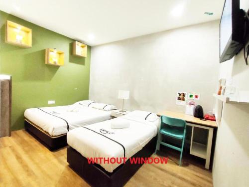 a room with two beds and a desk with a computer at Smile Hotel Danau Kota in Kuala Lumpur