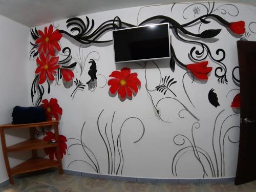 a room with a tv on a wall with flowers at Posada TEO in Xilitla