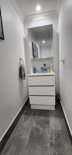 a white bathroom with a sink and a mirror at Oscar's at Banora in Kurrara