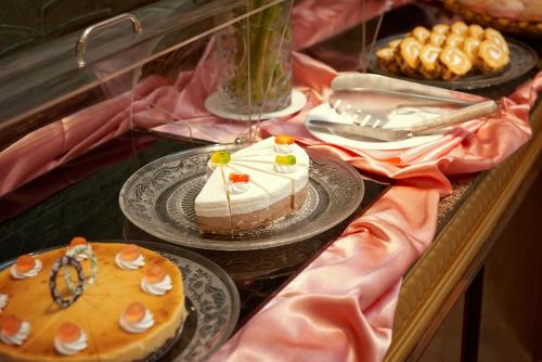 a display case with cakes on plates on a table at Khách sạn Quốc tế Lợi Lai - Li Lai International Hotel in Móng Cái