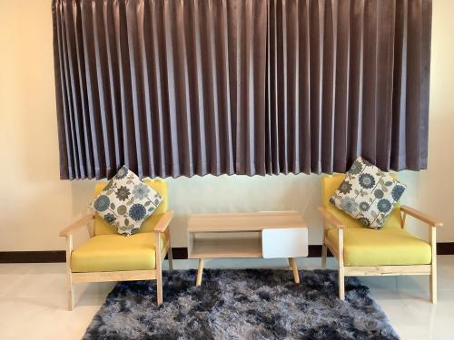 a living room with two chairs and a table at บ้านไร่โฮมเทล ณ ปากช่อง in Ban Nong Takhain