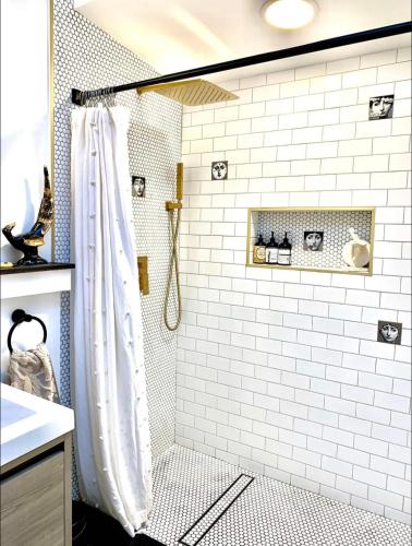 a bathroom with a shower with white tiles at Romantic cottage with amazing garden in Glendale