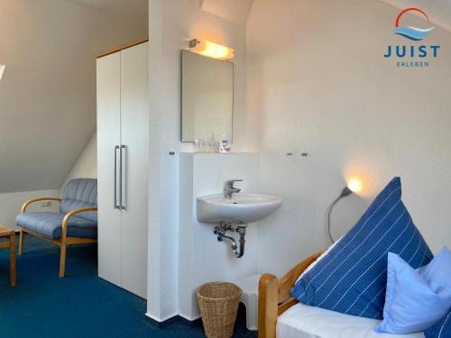 a bathroom with a sink and a mirror and a chair at Haus Augusta 163 - Ferienwohnung 3 in Juist