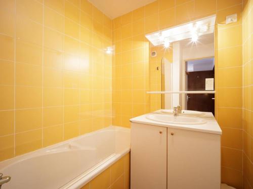 y baño amarillo con lavabo y bañera. en Appartement Peyragudes, 2 pièces, 6 personnes - FR-1-695-9, en Germ