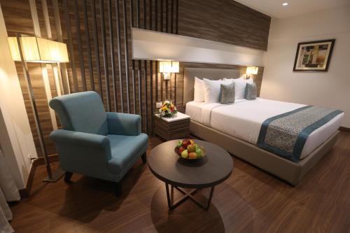 a hotel room with a bed and a chair and a table at Pharos Hotels in Chennai