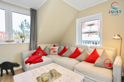 a living room with a white couch with red pillows at Haus Achterhus 213 - Wohnung 13 "rote Krabbe" in Juist