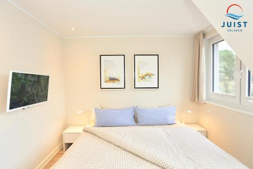 a white bedroom with a bed and two windows at Haus Achterhus 214 - Wohnung 14 "blauer Anker" in Juist