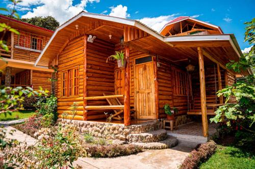 a wooden cabin with a porch and stairs in a yard at Fundo Hassinger in Oxapampa