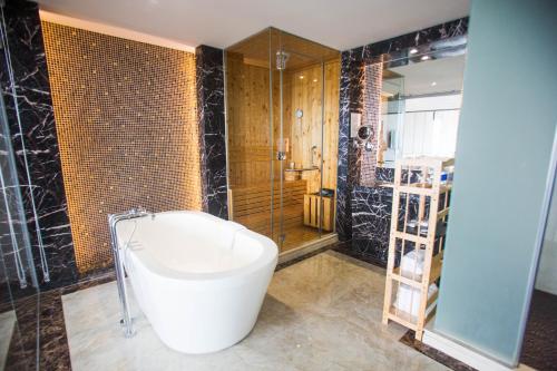 a bathroom with a tub and a shower and a toilet at The Mira Central Park Hotel in Bien Hoa