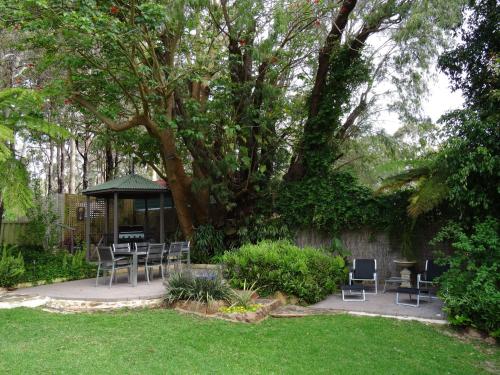 a garden with chairs and a gazebo with a tree at Edge Of The Forest Motel in Margaret River Town