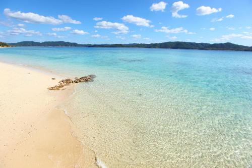 a beach with clear blue water and rocks in the sand at 泊まれるアートミュージアム 琉球ヴィラ in Tatsugo