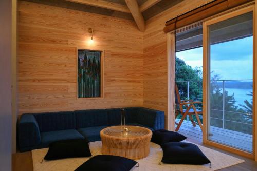a living room with a blue couch and a large window at 泊まれるアートミュージアム 琉球ヴィラ in Tatsugo