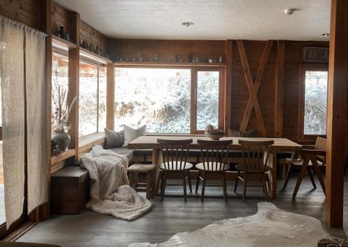 ein Esszimmer mit einem Tisch, Stühlen und einem Fenster in der Unterkunft Sugi Chalet in Myōkō