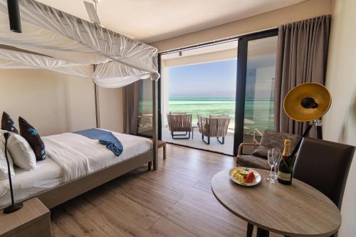 a hotel room with a bed and a table and a dining room at Villa Bluu Zanzibar in Jambiani