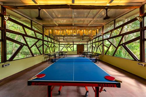 a ping pong table in a large room with windows at Kanha Jungle Camp in Kānha