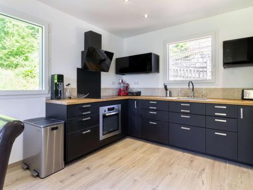 - une cuisine avec des placards noirs et un évier dans l'établissement Maison neuve à Grust pour 12 personnes, 4 chambres, WIFI, parking, linge et ménage inclus - FR-1-402-110, à Grust