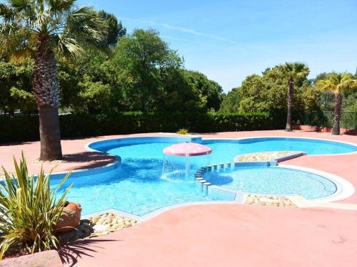- une piscine avec une fontaine et un palmier dans l'établissement Chalet climatisé avec piscine chauffée et parking dans une pinède calme - FR-1-607-64, à Agde