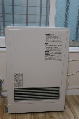 a white air conditioner sitting on a floor next to a window at attomi hostel in Sapporo