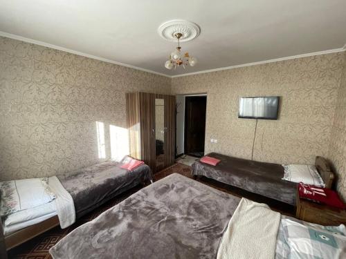 a bedroom with three beds and a chandelier at Guest House Eles in Karakol