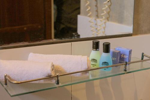 a glass shelf with two bottles of soap and towels at Woodnest Summerside in Negombo