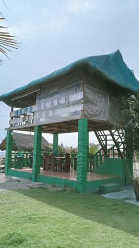 a building with a roof with tables and chairs at Mope Beach Resort in San Narciso