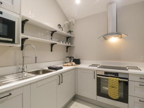 a kitchen with white cabinets and a sink and a microwave at Windermere in Kendal