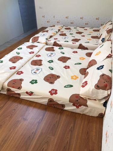 a bed with a blanket with bears on it at 嘉義行滿旅宿&包棟親子寵物烤肉平價好趣宿 in Zhuqi