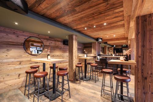 a bar with wooden walls and stools in a restaurant at No 8 Bed & Bar in Verbier