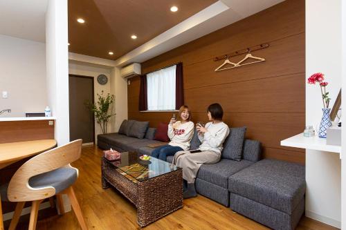 two people sitting on a couch in a living room at ゲストルーム心音-金澤表参道- in Kanazawa