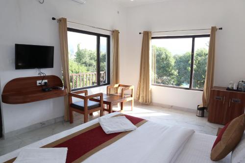 a bedroom with a bed and a desk and a television at Seven Corbett in Rāmnagar