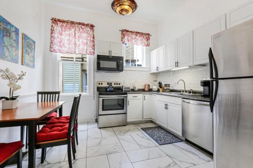 a kitchen with white cabinets and a table and a refrigerator at Uptown Spacious 4BD/3BA with Historic Charm in New Orleans