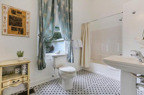 a bathroom with a toilet and a sink and a window at Uptown Spacious 4BD/3BA with Historic Charm in New Orleans
