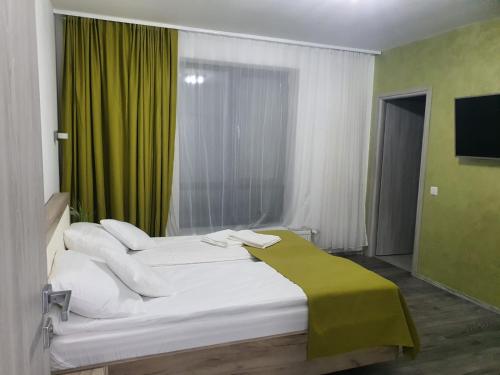 um quarto com 2 camas brancas e uma cortina verde em Vilă primitoare în Cihei ideală pentru grupuri. em Apateu