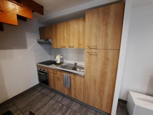 mała kuchnia z drewnianymi szafkami i zlewem w obiekcie Charmante petite maison w mieście Cholet