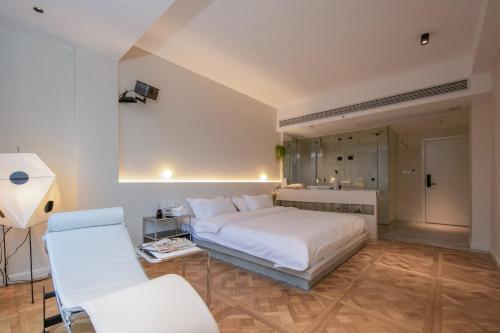 a bedroom with a white bed and two white chairs at IM Waiting Hotel in Yangshuo