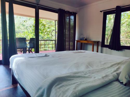 a bedroom with a large white bed and windows at Samyama Retreat in Cola