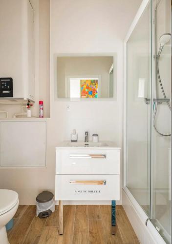 une salle de bain blanche avec un lavabo et une douche dans l'établissement Duplex-terrasse-parking-climatisation, à Bordeaux