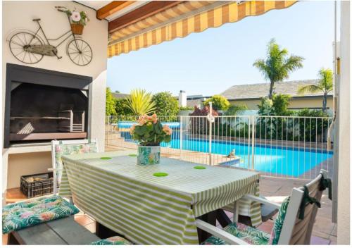 een tafel met een vaas met bloemen op een patio met een zwembad bij Meerendal Cottage-Affordable Luxury,Private Pool in Kaapstad